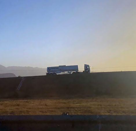 Modern post and delivery by car. Courier looks at tablet and hol